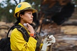 A wildland firefighter in full gear surveys the landscape.