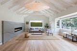 This living room features a custom concrete fireplace inlaid with copper, inspired by Japanese Kintsugi pottery. A glowing overhead light handmade from washi paper harkens a resemblance to whales and seashells, a quiet reference to the ocean nearby.