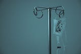 An iv pole with an iv bag, and blue mood lighting.