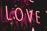 Pink neon lights create the word “love”.
