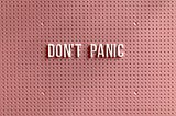 Pink sign saying “Don’t Panic”