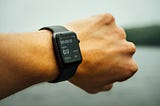 Left arm of a man with a smart watch on his wrist showing a fitness app.