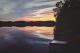 A picture of a lake at sunset with a slide going into the water.
