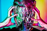 Two hands hold the side of a head, which is covered in tinfoil