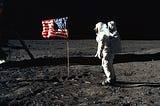 An astronaut walks toward an American flag on the moon.
