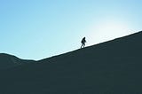 A lone person walking up a steep hill.