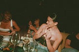 A group of women laughing and talking together at a dimly lit dinner party