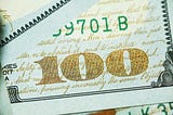 The number 100 is displayed prominently on the corner of a bank note.