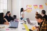 A team of people participating in an ideation session, sticking post-it notes on a wall