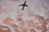 An airplane high among the clouds in the evening sky