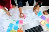 A team of ux designers applying reviewing wireframes based on brainstormed ideas.