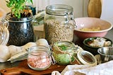 Ingredients, in bowls and open jars, laid out on a wooden surface.
