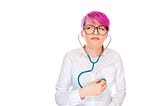 Young woman with colorful hair anxiously listening to her chest with a stethoscope