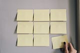 Nine Post-Its attached to the wall with a woman’s hand grabbing one
