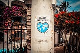 A light post with a poster on it saying Planet Earth First and an image of the world in the shape of a heart.