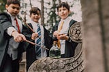 Thee boys in Hogwarts’ robes and ties, each one holding a wand, as if casing a magic spell,