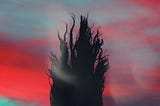 Silhouette of a woman with hair in wind with a bright red and blue sunset as a back drop.