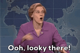 Gif of SNL actress, white woman with purple shirt, likely portraying Elizabeth Warren, sits in front of a blue world map. She points at something off camera and says Ooh, looky there!