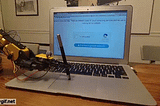 GIF av en robotarm som fører en penn på musen på en datamaskin for å bevise at hen ikke er en robot.
