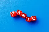 A sky blue background with the word “panic” on red cubed beads with white letters.