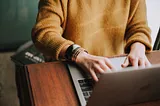 Woman sitting at a desk writing on an open laptop