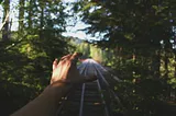 A hand stretched towards a rail track.