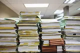 Sheets of paper stacked high on a desk.