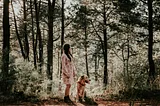 Woman with dog, in woods