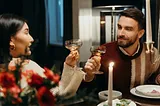 A couple toasting each other in a candlelit dinner