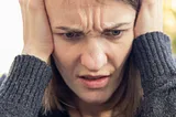 A young woman holds her head in frustration.