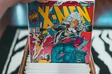 Somebody pulling an X-Men comic book from a box of comics.