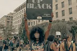 A Black woman holding up a sign saying I wake up Black at a demonstration for Black Lives Matter.