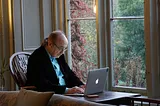 Older gentleman tapping on a laptop