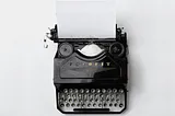 An old black typewriter with a white sheet of paper. White background.