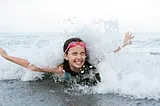 Little girl splashing on the shore with a happy expression on her face, arms spread out