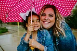 Mother hugging daughter under an umbrella