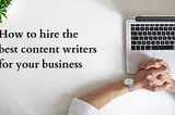 The picture shows the topview of a laptop sitting open on a table. A person’s hands are resting on the table and on the top left corner, we can see a small green plant. The right side of the image shows the text “How to hire the best content writers for your business”