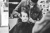 Black and white photo of young kid in barber chair