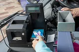 A photograph of a passenger tapping their NEC card on a reader as they board a bus (photo was sourced from Transport Scotland)