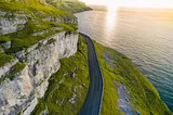 A mountain road next to a cliff that leads to the ocean.