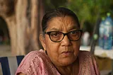 Elderly Indian woman looking pensive, wearing glasses