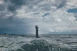 A man reaches forth in the middle of the ocean, asking for help