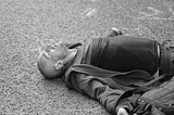 Exhausted man lying down in street.