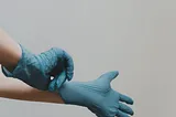 doctor putting on a blue nitrile or rubber glove
