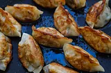 Korean dumplings (mandu) sizzling in a frying pan