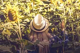 A woman standing in vegetation that is taller than she is.