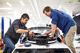 Two Cruise employees work on the self-driving sensors on a Cruise self-driving vehicle.