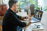 A man is having a zoom meeting. His desk isn’t messy.