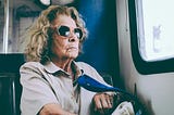 older woman wearing glasses sitting in a bus
