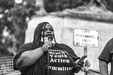 Zyahna Bryant speaking into a micriphone before the Charlottesville statue of Robert E. Lee.